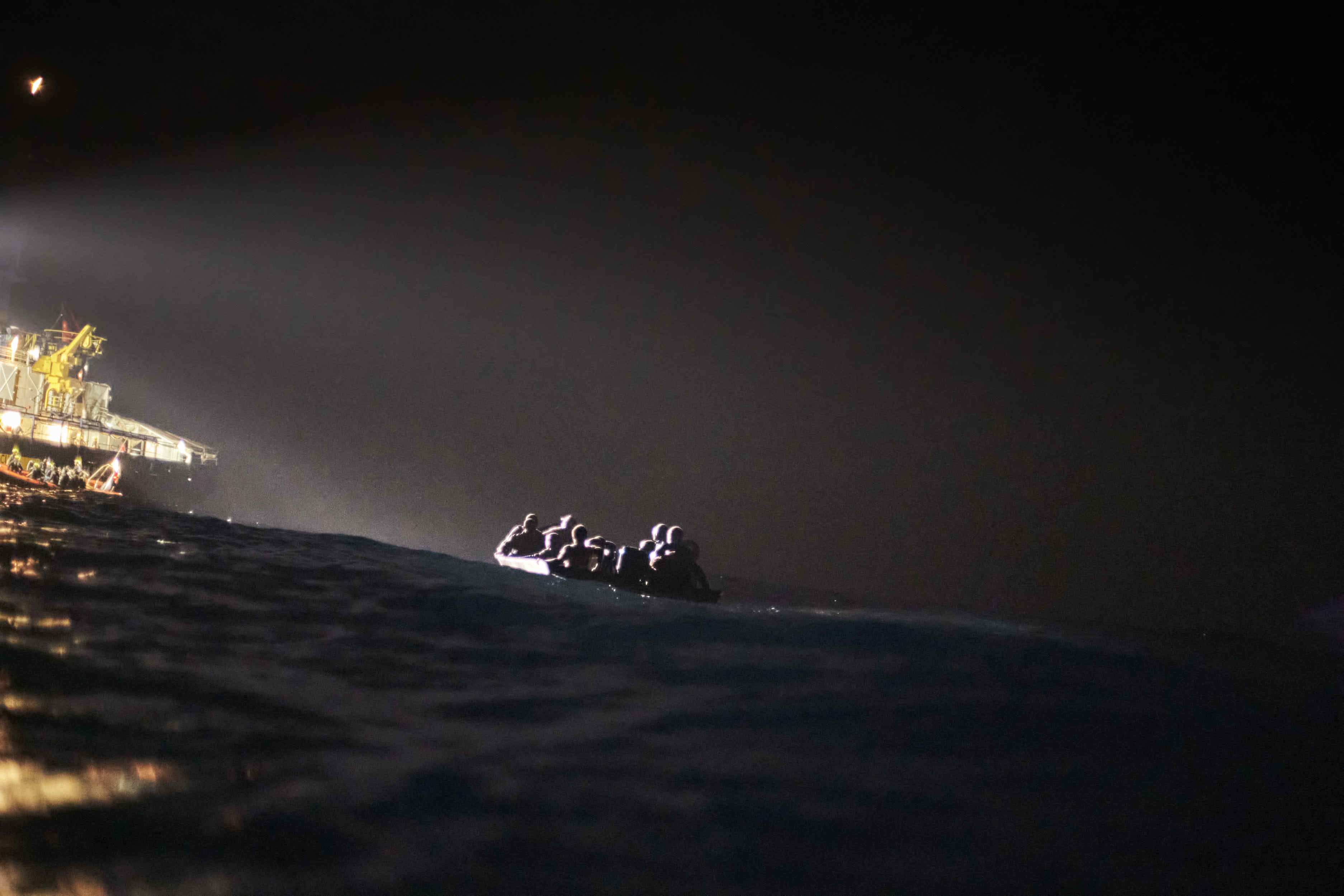 Ein Seenotrettungsschiff strahlt nachts auf dem Meer ein Boot mit Geflüchteten an (Quelle: Raphael Schumacher(SOS Humanity)