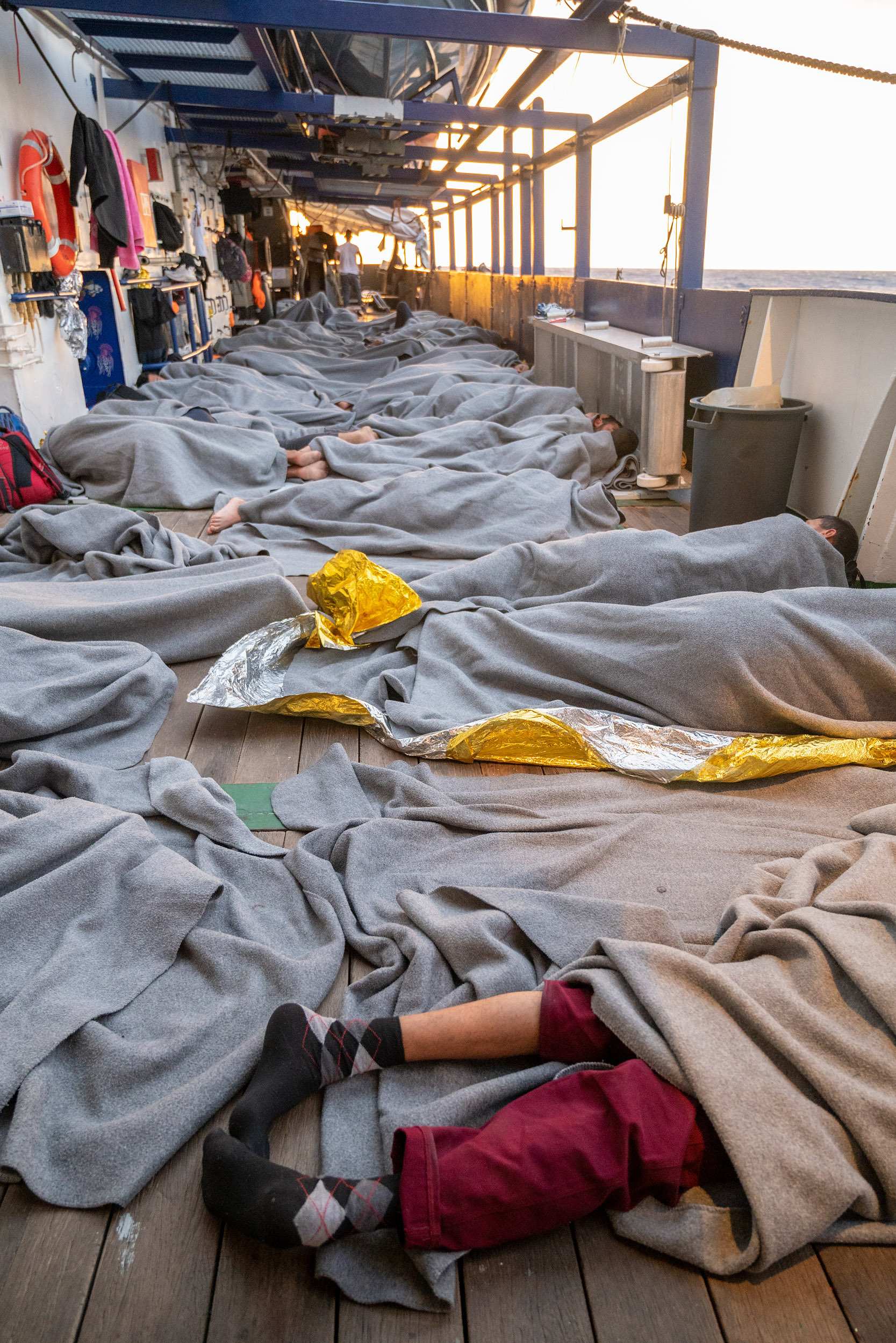 Auf einem Schiiffsdeck liegen viele schlafende Menschen unter Decken (Quelle: Arez Ghaderi/SOS Humanity)