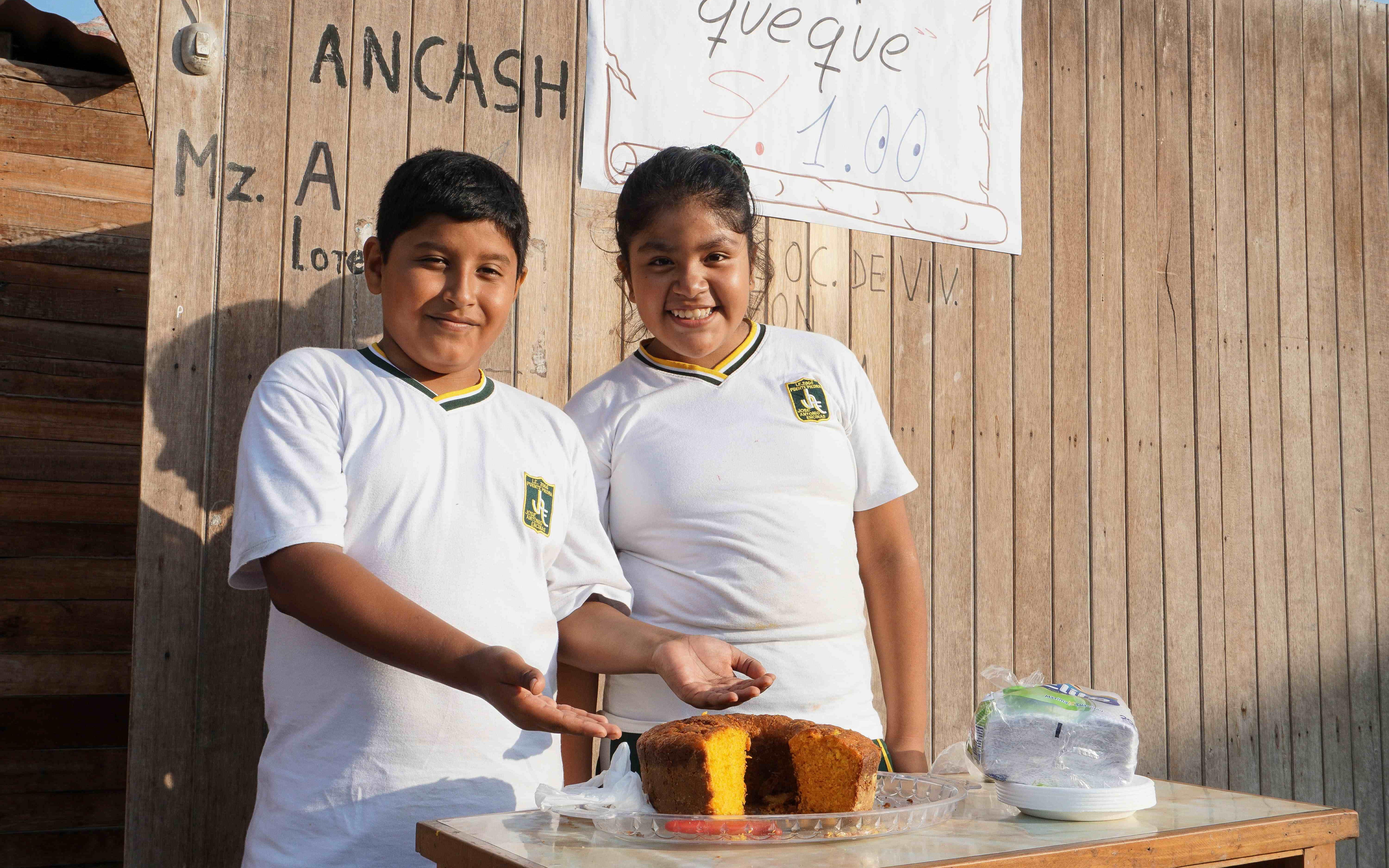 Reportage Peru: "Von Selbstvertrauen und Kinderrechten"; Foto: Zwei Kinder präsentieren Kuchen (Quelle: Lorenz Töpperwien / Kindernothilfe)