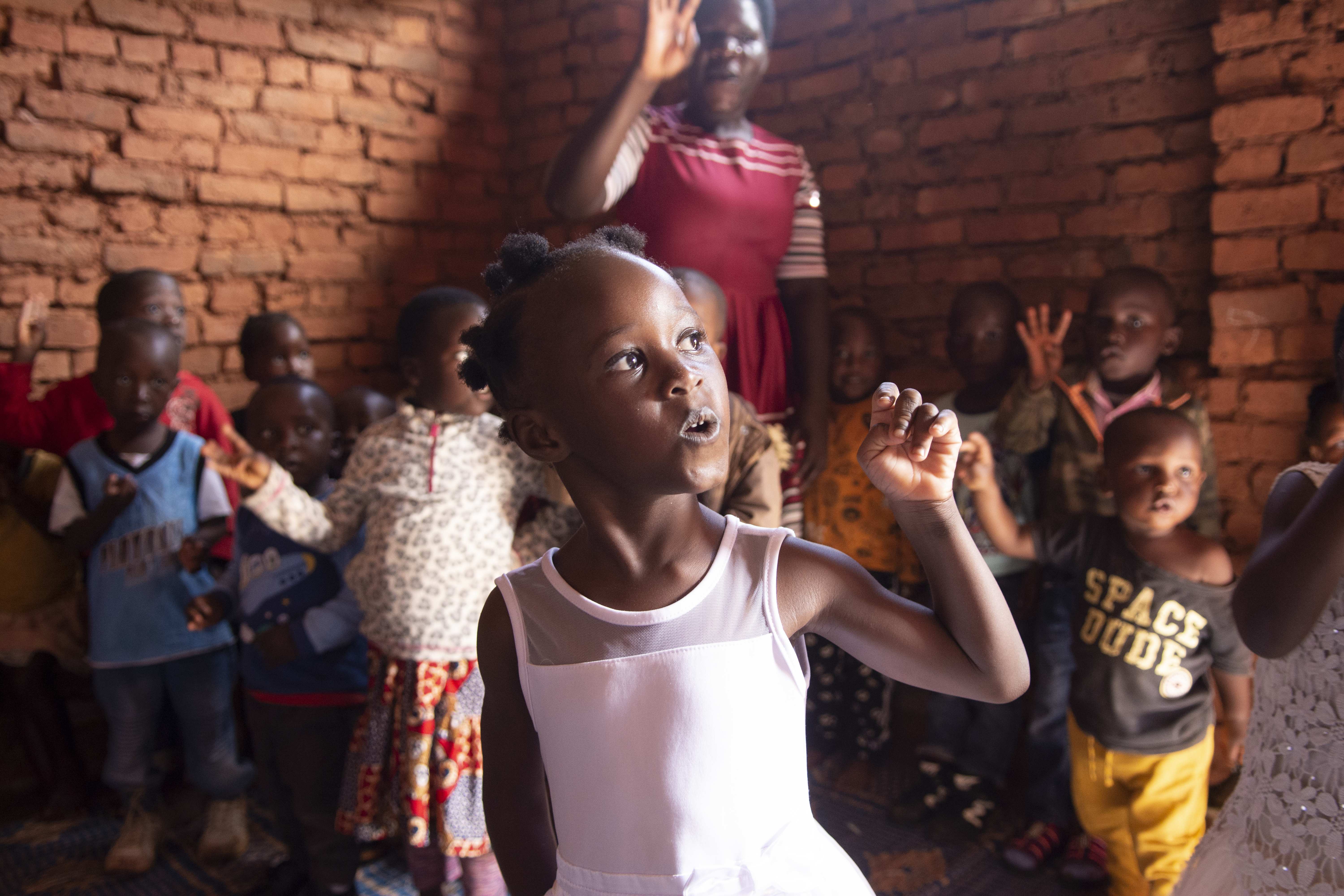 Ein Mädchen mit zerebraler Kinderlähmung steht in Malawi in ihrem Kindergarten. Im Hintergrund sind andere Kindergartenkinder und ihre Lehrerin (Quelle: Christian Nusch) Ein Mädchen mit zerebraler Kinderlähmung steht in Malawi in ihrem Kindergarten. Im Hintergrund sind andere Kindergartenkinder und ihre Lehrerin (Quelle: Christian Nusch)