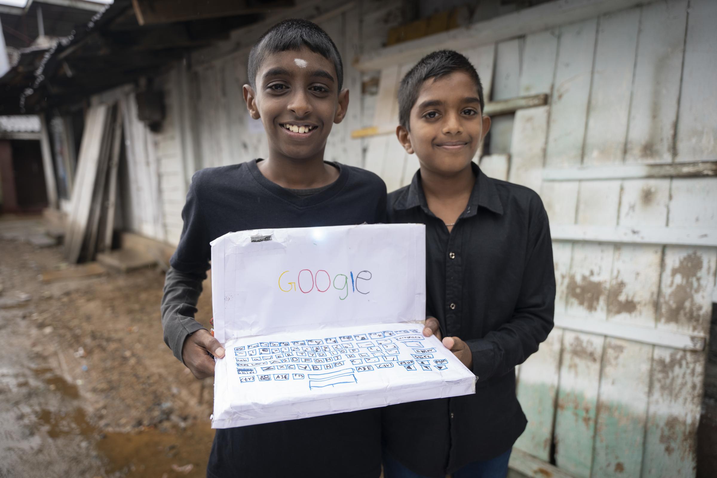 Zwei Jungen zeigen einen aus Papier gebastelten Laptop (Quelle: Christian Nusch) Platzhalterbild