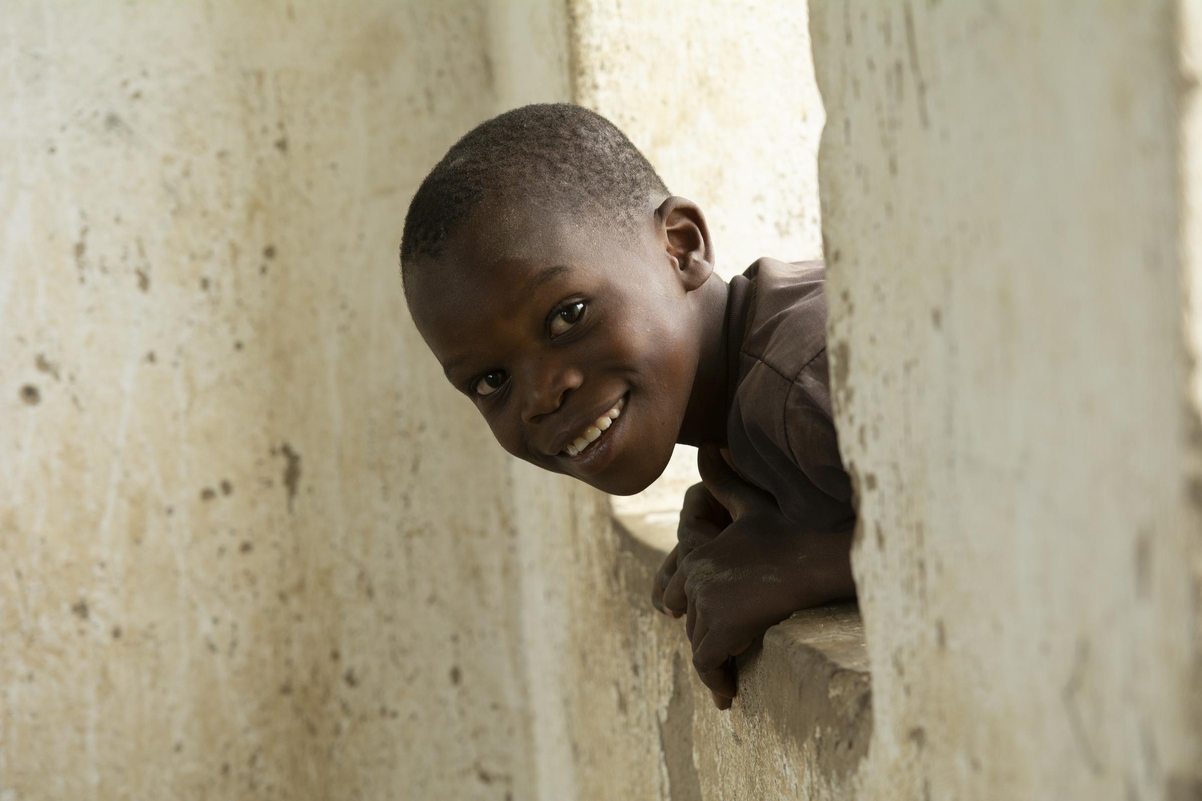 Lachender Junge schaut durch ein Fenster rein (Quelle: Christian Nusch)