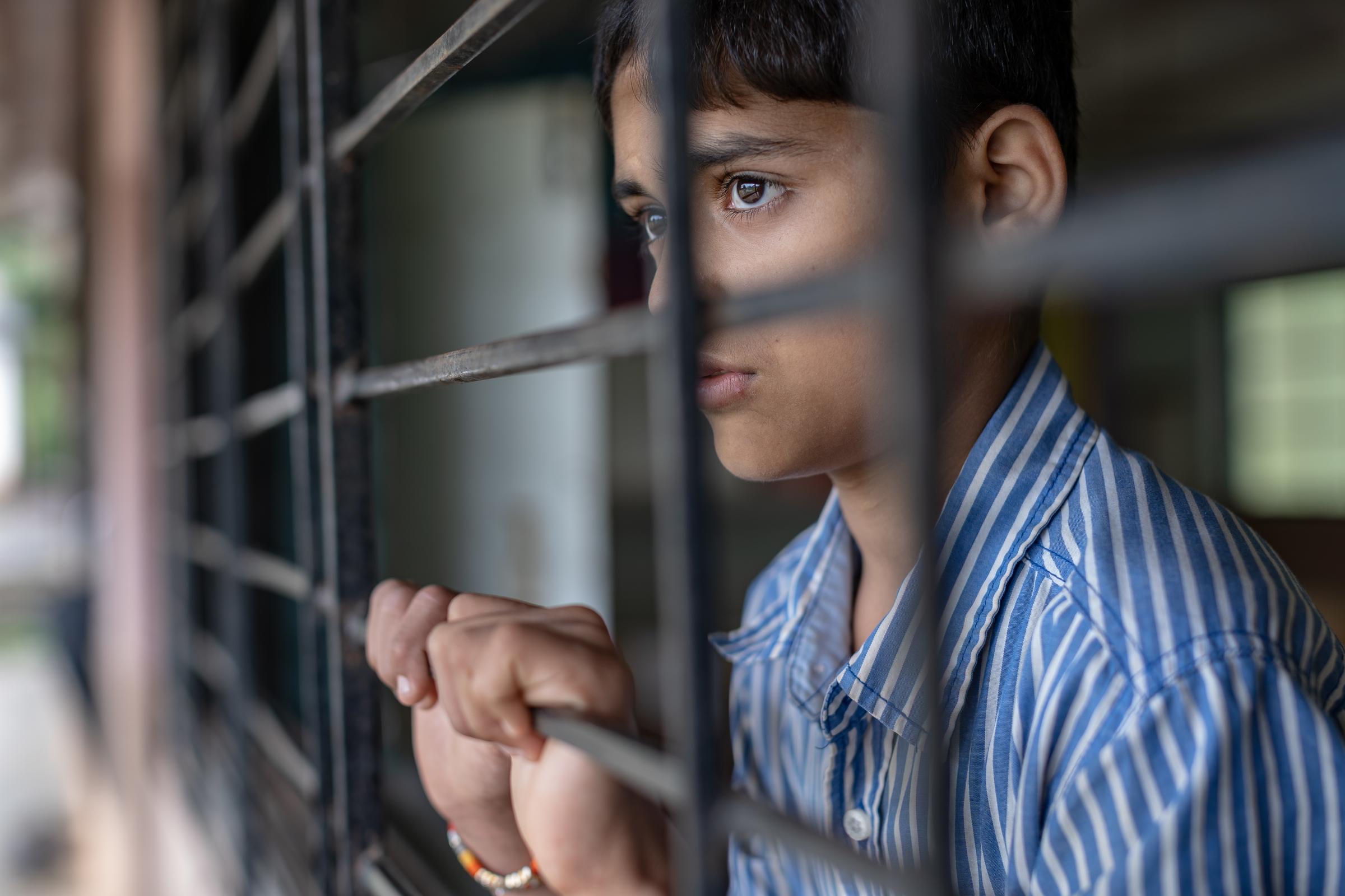 Junge hinter Gitter blickt nach draußen (Quelle: Jakob Studnar)