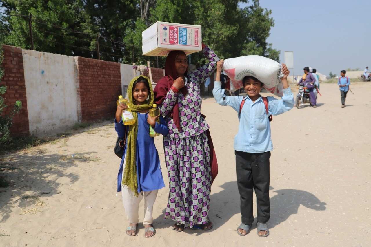 Eine Frau steht mit einem Mädchen und einen Jungen auf der Straße, alle haben Essenspakete in der Hand (Quelle: Kindernothilfe)