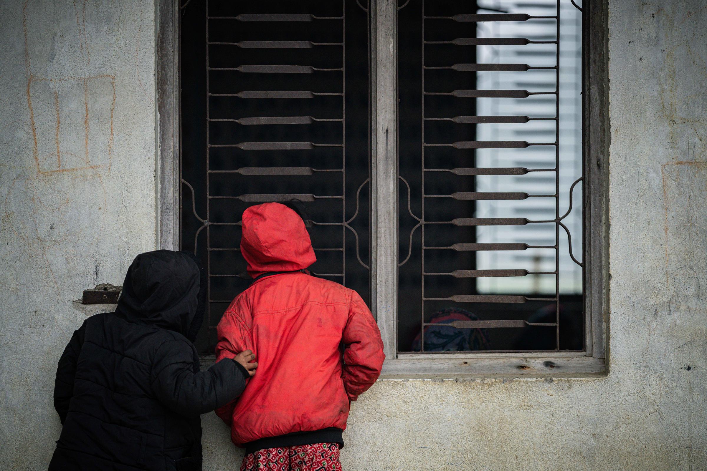 Zwei Kinder sind von hinten zu sehen und schauen durch ein Fenster nach drinnen Foto : Jakob Studnar /  Kindernothilfe.