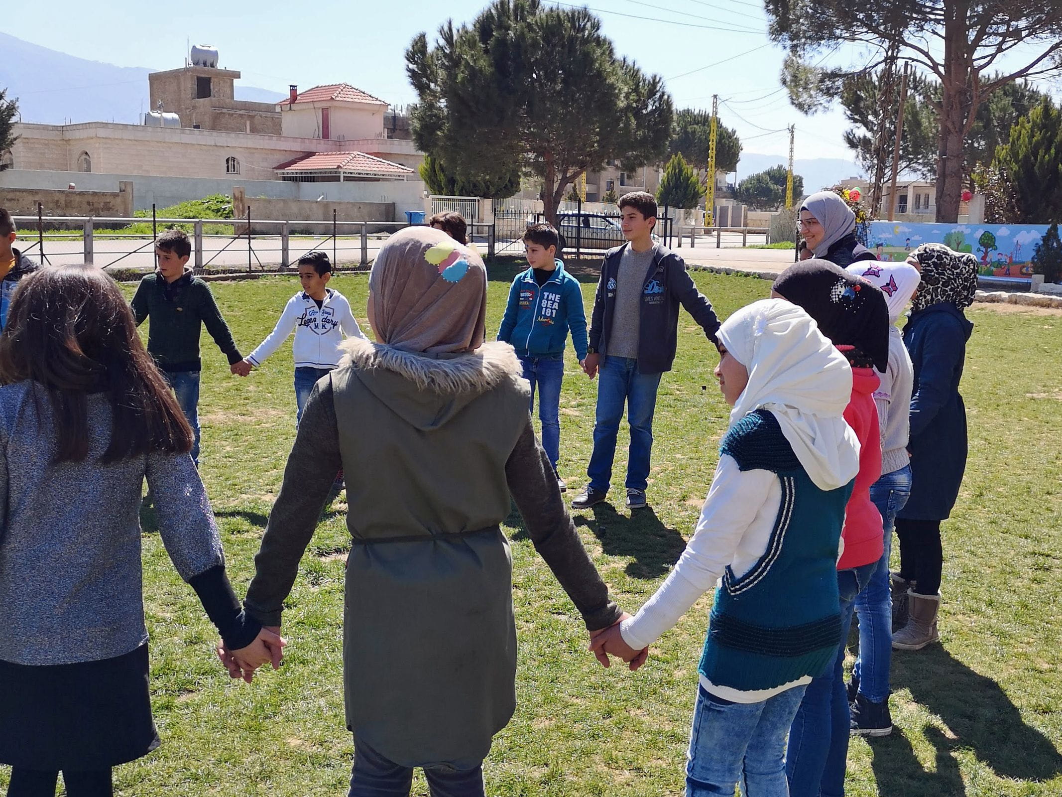 Jugendliche stehen im Kreis auf einer Wiese und halten sich an den Händen. (Quelle: Lorenz Töpperwien) Jugendliche stehen im Kreis auf einer Wiese und halten sich an den Händen. (Quelle: Lorenz Töpperwien)